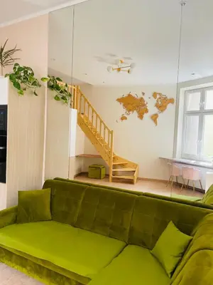 a green couch in a living room with a staircase at Nowoczesny Apartament w Centrum Krakowa in Kraków