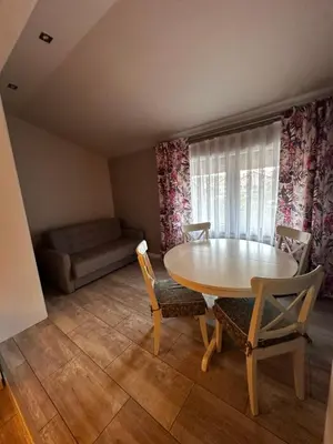 a dining room with a table and chairs and a couch at Apartamenty Czerwona Róża in Wieprz