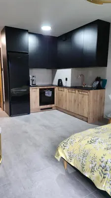 a kitchen with black cabinets and a bed in a room at Your time in Heart of Cracow , Gym & free parking in Kraków