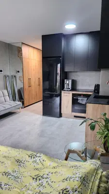 a kitchen with black cabinets and a couch and a table at Your time in Heart of Cracow , Gym & free parking in Kraków