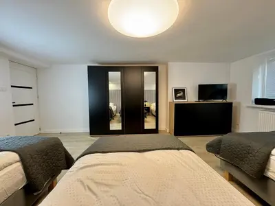 a bedroom with two beds and a flat screen tv at Apartamenty Oracka Przystań Solna 1 in Bochnia