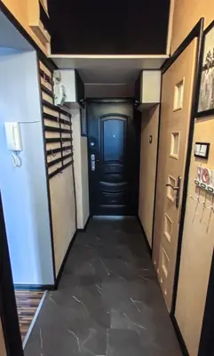 a hallway with a black door and a room with a refrigerator at Sweet Home Apartament in Kraków