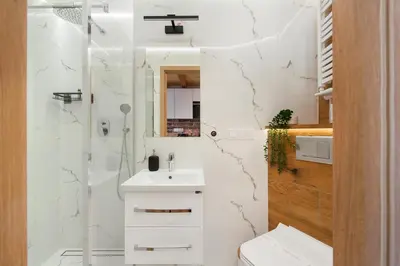 a white bathroom with a sink and a shower at Apartamenty przy Kładce- Kazimierz Old Town in Kraków