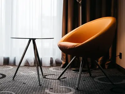 a orange chair and a side table in front of a window at Q Hotel Plus Kraków in Kraków