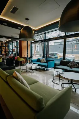 a living room with couches and tables and windows at Q Hotel Plus Kraków in Kraków