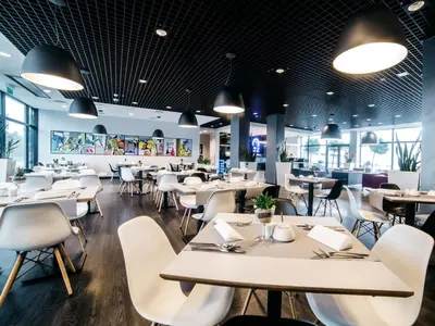 a restaurant with white tables and chairs and windows at Q Hotel Kraków in Kraków
