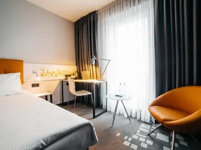a hotel room with a bed and a chair and a desk at Q Hotel Kraków in Kraków