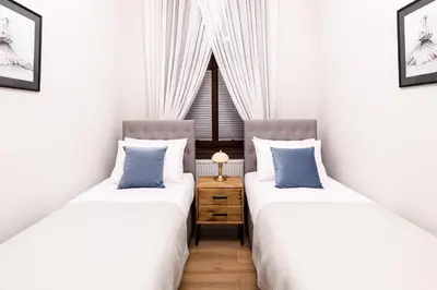 two beds in a room with white walls and blue pillows at Family AC apartment Old Town Main Railway Station in Kraków