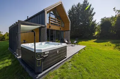 a small house with a hot tub on a deck at Piotrowiczówka Osada w Szczyrzycu in Szczyrzyc