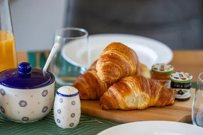a wooden cutting board with croissants and a cup of jam at Piotrowiczówka Osada w Szczyrzycu in Szczyrzyc