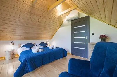 a bedroom with two beds and a blue chair at Piotrowiczówka Osada w Szczyrzycu in Szczyrzyc