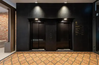 two black doors in a hallway with a rug at Wawel View Stylish Apartment in Kraków
