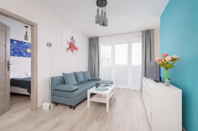 a living room with a blue couch and a tv at Cozy Apartments Łaszkiewicza with Parking by Noclegi Renters in Kraków