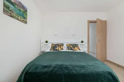 a bedroom with a bed with a green comforter at Cozy Apartments Łaszkiewicza with Parking by Noclegi Renters in Kraków