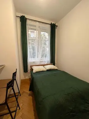a bedroom with a green bed and a window at Krowoderska Lovely Room in Kraków