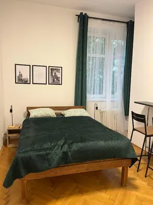 a bedroom with a bed with a green blanket on it at Krowoderska Lovely Room in Kraków