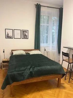 a bedroom with a bed with a green blanket at Krowoderska Lovely Room in Kraków