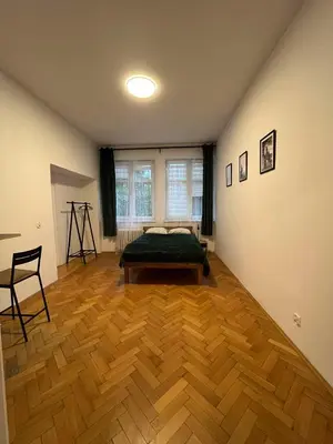 a bedroom with a bed and a wooden floor at Krowoderska Lovely Room in Kraków