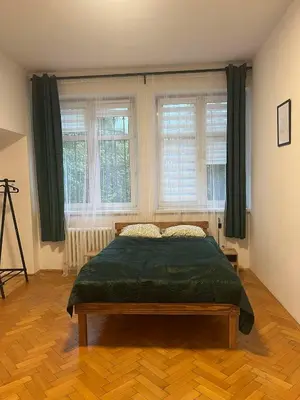 a bedroom with a bed in a room with windows at Krowoderska Lovely Room in Kraków