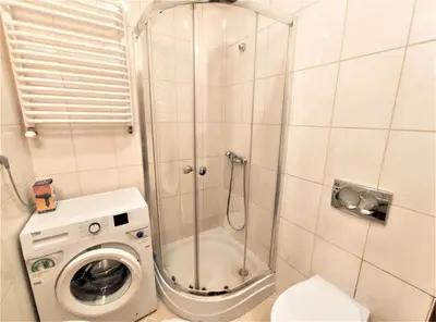 a bathroom with a shower and a washing machine at Abak Krakow Apartment in Kraków