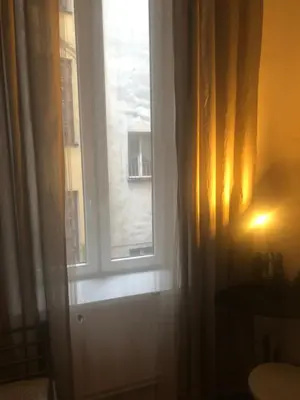 a window in a room with a curtain and a toilet at Mini in Kraków