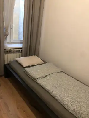 a bed with two pillows sitting next to a window at Mini in Kraków