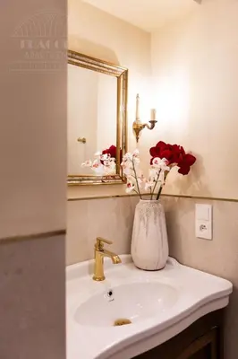 a bathroom sink with a vase with red roses in it at Fragola Apartments Le Jardin - classy, spacious Old Town apartments in Kraków