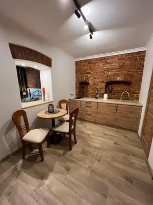 a kitchen with a table and chairs and a brick wall at Apartamenty K9 in Kalwaria Zebrzydowska