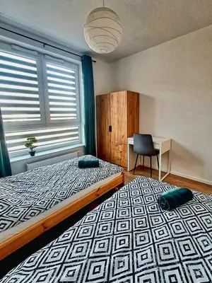 a bedroom with a bed and a chair and a window at Apartament Bazylek, miejsce parkingowe w garażu podziemnym in Kraków