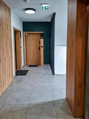 an empty hallway with wooden doors and a tile floor at Apartament Bazylek, miejsce parkingowe w garażu podziemnym in Kraków