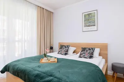 a hotel room with two beds with a green blanket at Przytulny i Przestronny Apartament w Krakowie z Parkingiem Biurkiem i 2 Balkonami by Noclegi Renters in Kraków