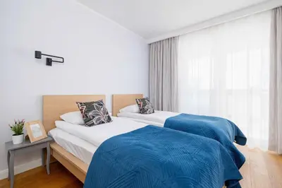 a bedroom with two beds with blue sheets and a window at Przytulny i Przestronny Apartament w Krakowie z Parkingiem Biurkiem i 2 Balkonami by Noclegi Renters in Kraków