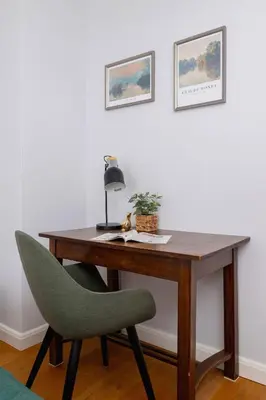 a wooden desk with a green chair and a lamp at Przytulny i Przestronny Apartament w Krakowie z Parkingiem Biurkiem i 2 Balkonami by Noclegi Renters in Kraków