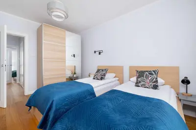two beds in a room with white walls and blue sheets at Przytulny i Przestronny Apartament w Krakowie z Parkingiem Biurkiem i 2 Balkonami by Noclegi Renters in Kraków