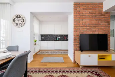 a living room with a tv and a brick wall at Przytulny i Przestronny Apartament w Krakowie z Parkingiem Biurkiem i 2 Balkonami by Noclegi Renters in Kraków