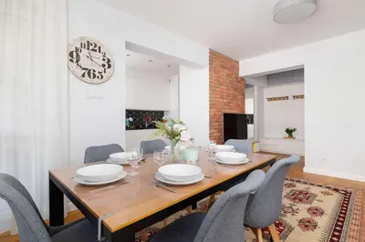 a dining room with a wooden table and chairs at Przytulny i Przestronny Apartament w Krakowie z Parkingiem Biurkiem i 2 Balkonami by Noclegi Renters in Kraków