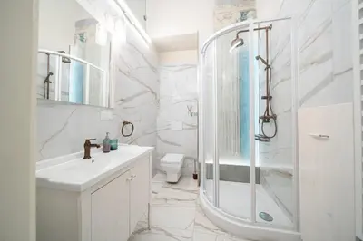 a white bathroom with a shower and a sink at Apartamenty pod Jagnięciem - Rynek Główny in Kraków