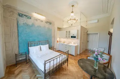 a bedroom with a bed and a table and a kitchen at Apartamenty pod Jagnięciem - Rynek Główny in Kraków