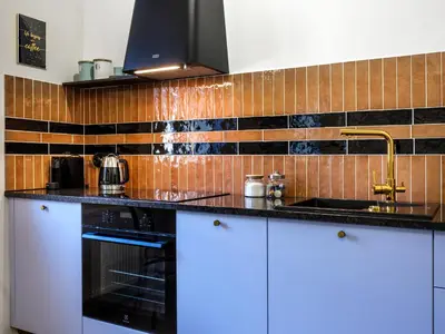 a kitchen with white cabinets and a sink and tiles at Kalwaryjska by Tyzenhauz in Kraków