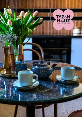 a table with two cups and a vase with flowers at Kalwaryjska by Tyzenhauz in Kraków