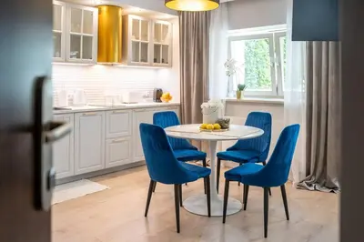 a kitchen with a table and blue chairs at Apartment w ogrodzie w sercu starego Krakowa in Kraków