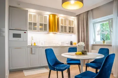 a kitchen with a table and blue chairs at Apartment w ogrodzie w sercu starego Krakowa in Kraków