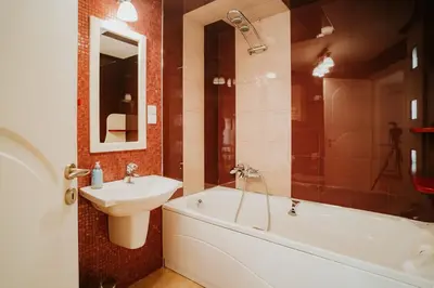 a bathroom with a sink and a tub and a toilet and a mirror at Apartamenty pod Dzwonkiem in Wadowice