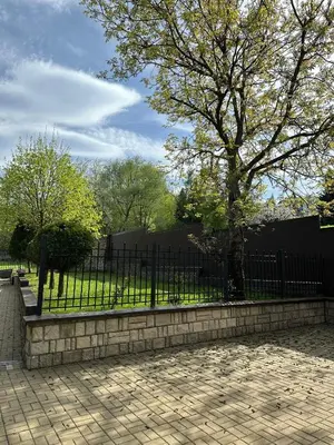 a fence in front of a park with trees and grass at Apartamenty pod Dzwonkiem in Wadowice