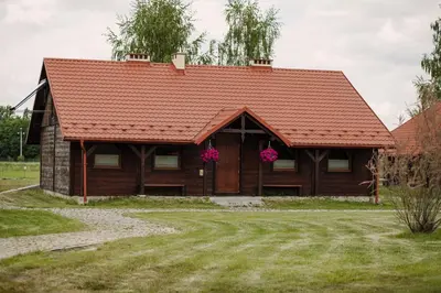 a house with a red roof and pink flowers at Centrum Aktywnego Wypoczynku Borek in Rzezawa
