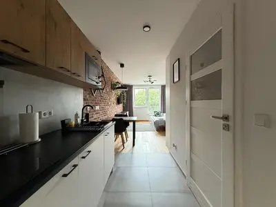 a kitchen with white cabinets and a black counter top at Halicka Apartment Free Parking by CityBeat in Kraków