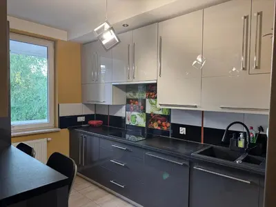 a kitchen with white cabinets and a black counter top at Supreme Luxury Apartment in Kraków