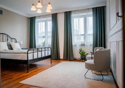 a bedroom with a bed and a chair and windows at Apartament Clover by Meadow Stay Apartments in Kraków