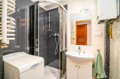 a small bathroom with a shower and a sink at Apartament Clover by Meadow Stay Apartments in Kraków