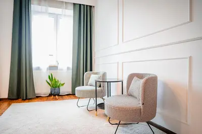 two chairs and a table in a room with a window at Apartament Clover by Meadow Stay Apartments in Kraków